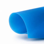 A close-up of a Bondi blue minukini, curled at the edge, photographed on a clean white background.